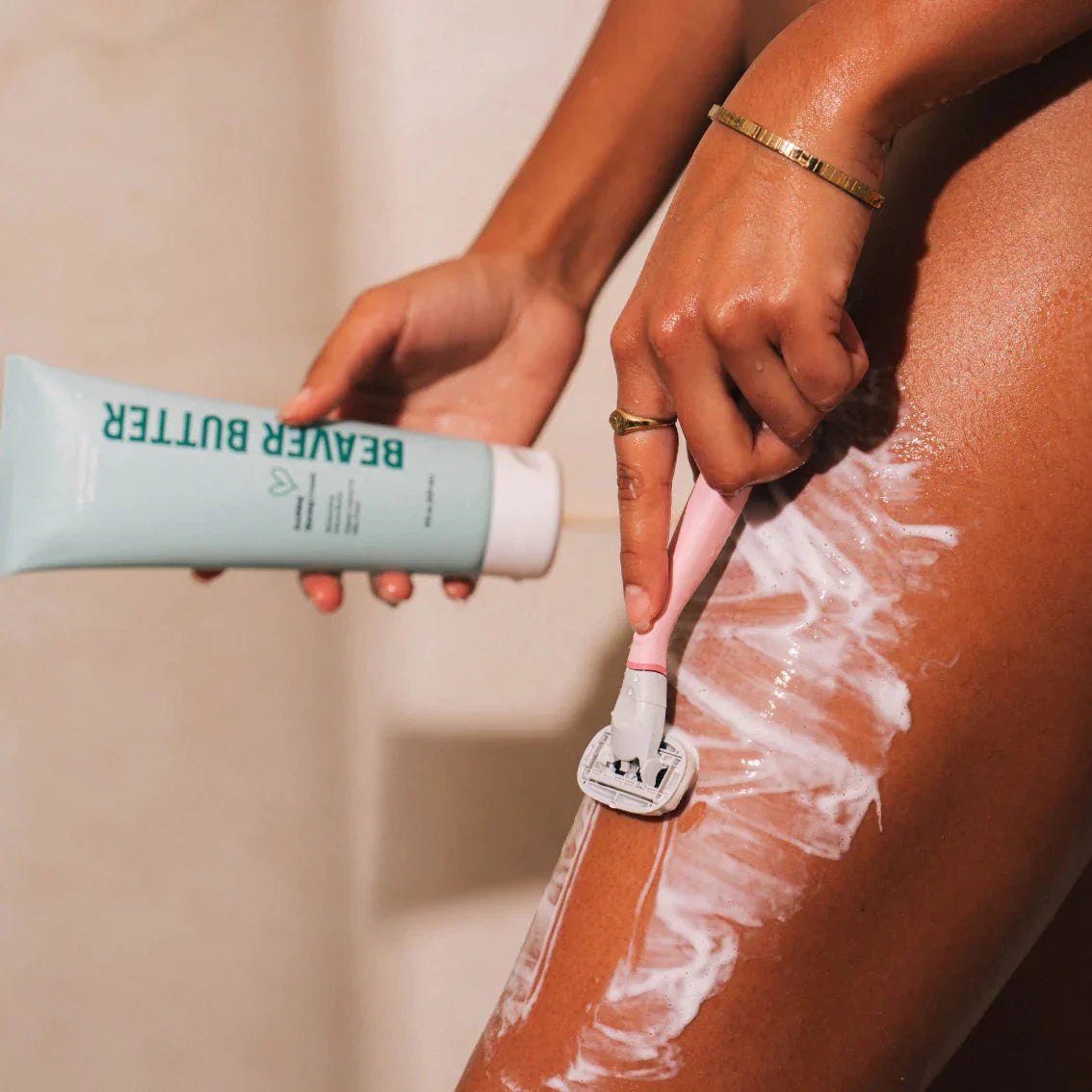 Someone shaving with Beaver Butter soothing shaving cream and holding a tube.